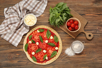 Tasty pizza and ingredients on wooden background