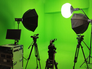 A green screen studio room used to record footage and content is equipped with a video camera and lighting system.