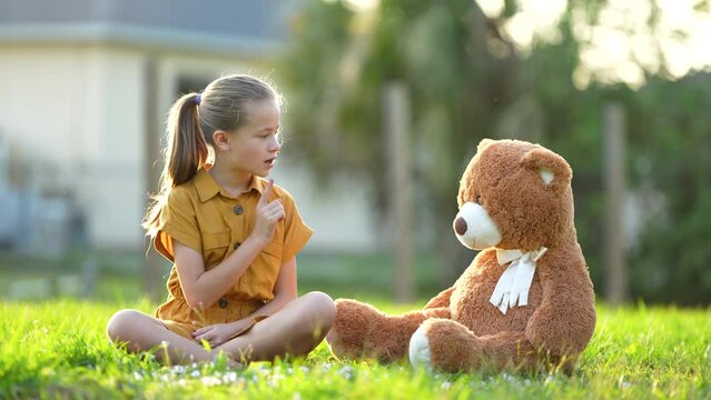 Unhappy child girl having an argument with her teddy bear friend. Concept of friendship difficulties