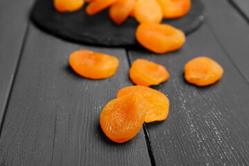 Tasty dried apricots on black wooden background