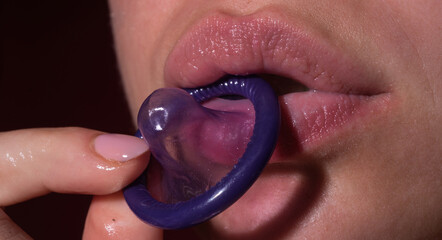 Girl lick suck condom. Foreplay before love. Close up woman mouth holding condom. Love, sexuality...