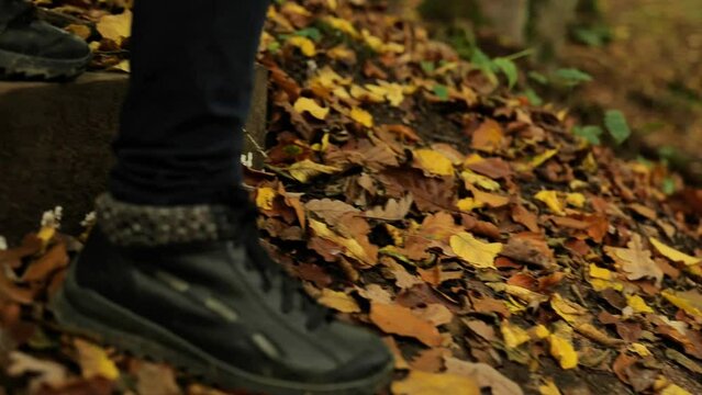 Walk in the autumn forest.Legs in leather boots go down the wooden stairs in the autumn forest. Slow motion.Child in the forest. 4k footage