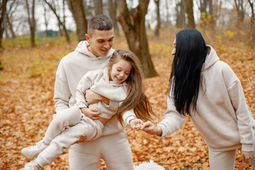 Young family standing in autumn forest and hugging