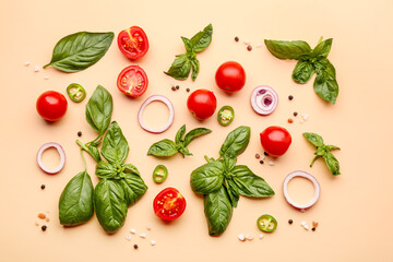 Fresh basil, cherry tomatoes and slices of red onion on orange background