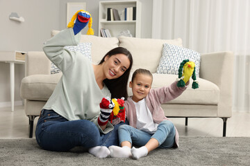 Happy mother and daughter playing with funny sock puppets together at home