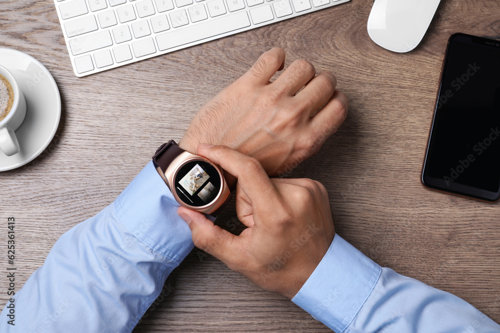 Poster businessman checking home security system via smartwatch app at office table, top view. image of roo