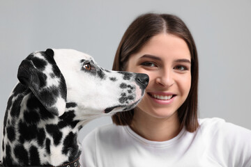 Beautiful woman with her adorable Dalmatian dog on light grey background, selective focus. Lovely pet