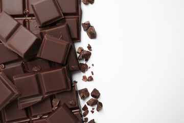 Pieces of delicious dark chocolate bars on white background, flat lay. Space for text