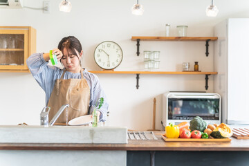 洗い物をするエプロン姿の女性・主婦（疲労）
