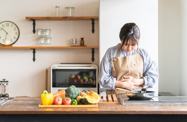 料理中に体調不良になるエプロン姿の女性・主婦（お腹）
