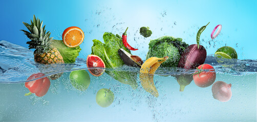 Many fruits and vegetables falling into water against blue background