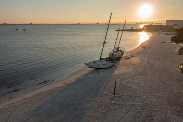 Sailboats washed ashore on a beach during sunset. Shipwreck.