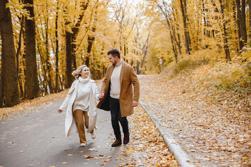 Fototapeta premium Romantic couple walking in autumn forest and holding hands