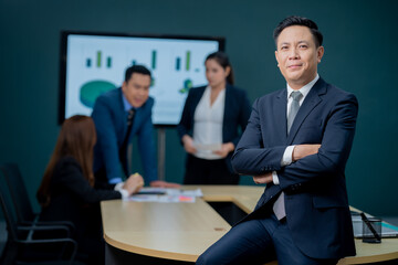 Fototapeta na wymiar Handsome Asian middle-aged executives business man standing confident in the office in front of his team.