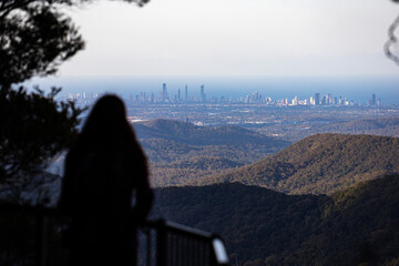 silhouette of a pretty woman admiring the sunrise over a canyon in springbrook national park,...