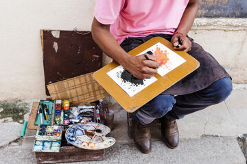 african american man artist or painter in the street painting on footpath in Latin America, Afro...