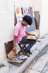 african american man artist or painter in the street painting on footpath in Latin America, Afro...