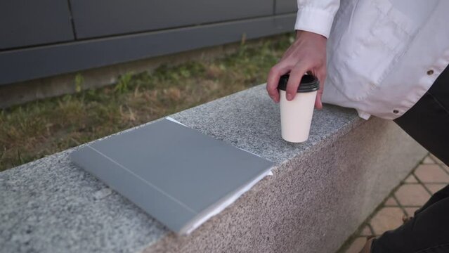 Tired male doctor taking coffee break in backyard of hospital. Exhausted physician throws folder with documents, patient's medical history and takes cup coffee while enjoying hot drink near the clinic