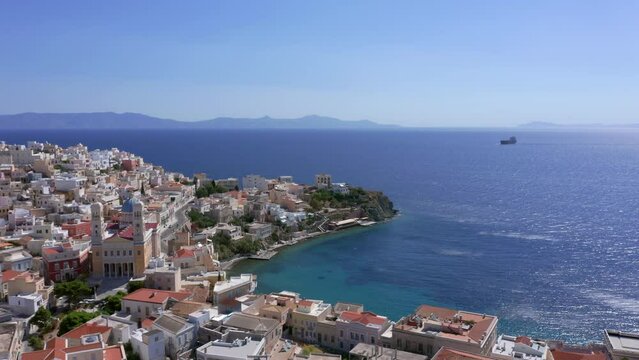 Aerial: Slow panning shot of Asteria Beach in Ermoupoli of Syros island, Greece on a sunny day