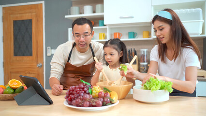 Happy Asian family with father, mother, and little girl enjoy cooking and having a breakfast together.