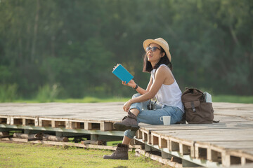 asian woman traveler with backpack relaxing outdoor with sitting on quayside relax read book during...