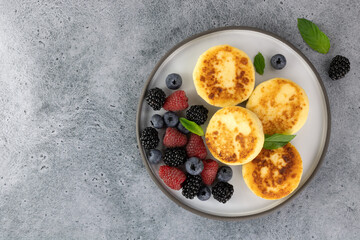 Syrniki or cottage cheese pancakes with berries on blue background. Top view. Copy space. Russian, ukrainian food