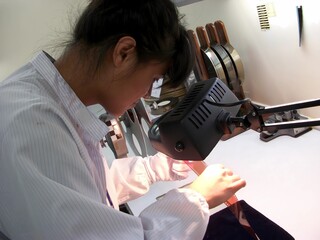 A man wearing a white shirt gown using a inspection a negative film 35mm for QC to standard.