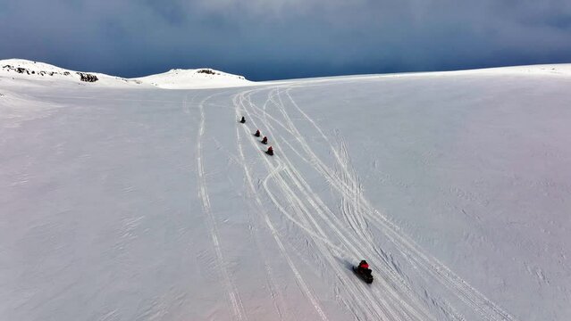 Aerial view of people riding snowmobiles on the icy ground of Myrdalsjokull glacier in Iceland