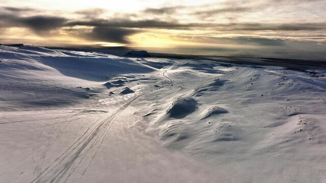 Aerial landscape view of people riding snowmobiles on Myrdalsjokull glacier in Iceland, during an epic sunset