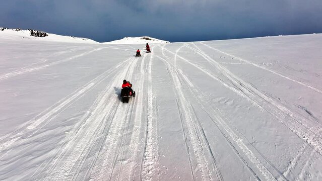 Aerial view over people riding snowmobiles on the icy ground of Myrdalsjokull glacier in Iceland