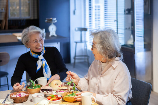 ランチでベーグルサンドを食べるシニア女性たち