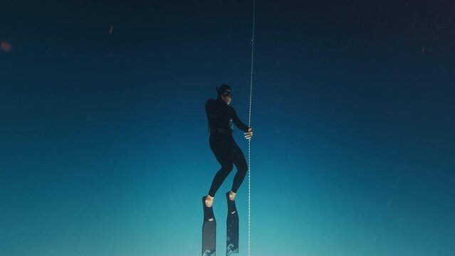 Freediver works out on rope. Man free diver trains along the rope in the open sea and descends to the depth