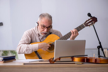 Old male music teacher in the classroom