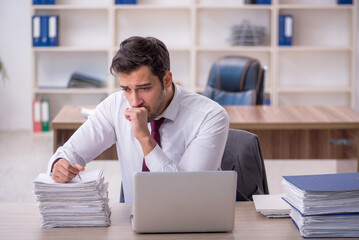 Fototapeta premium Young male employee and too much work at workplace