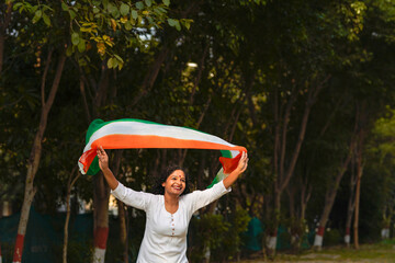 Indian woman waving tricolor cloth or odhani at park.