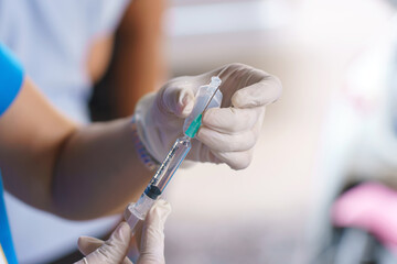 Doctor hands holding a vaccine bottle and syringe with needle filling with transparent fluid. - 625409696
