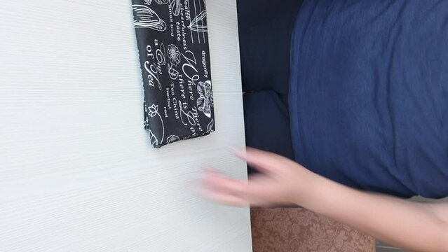 A woman reviews a kitchen towel. He takes it out of the box and puts it on the table. vertical video.