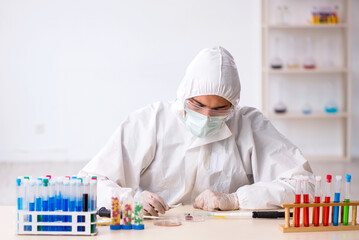 Young male chemist in drugs synthesis concept