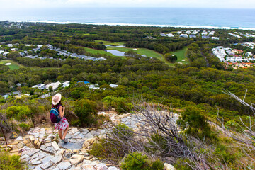 hiker girl in a hat walking down the stairs from the top of mount coolum; hiking famous mount...