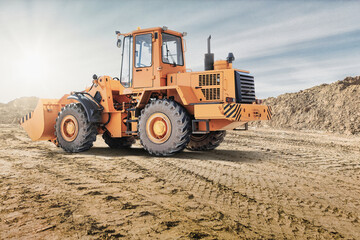 Wheel front loader or bulldozer at a construction site in a quarry. Powerful modern equipment for earthworks. Construction site. Rental of construction equipment.