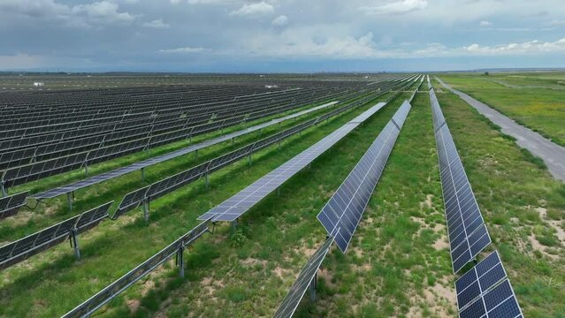 Solar panels facing different directions to optimize and maximize energy production on photovoltaic array farm. Aerial establishing shot.