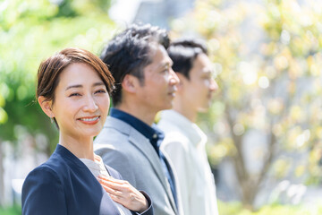 屋外の新緑の前に立つビジネスマンたち