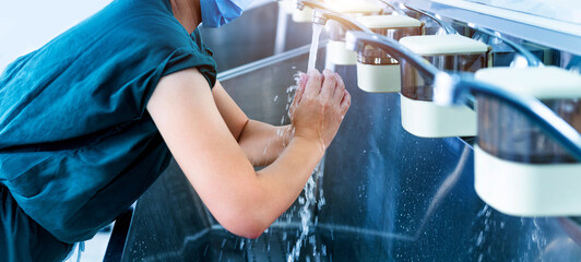 Young female doctor washing hands before operation