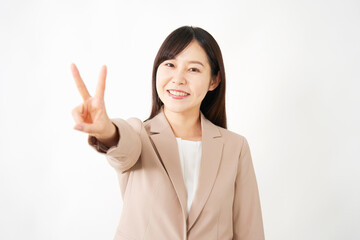 ピースサインをするミドルエイジのビジネスウーマン　白背景