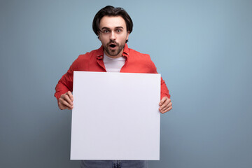 handsome caucasian brunet young man holding billboard with mockup