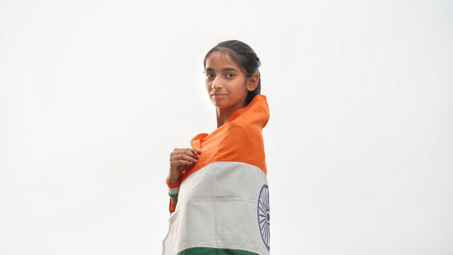 Cute Indian girl holding Indian flag in her hand and smiling. Celebrating Independence day or Republic day in India. A girl showing pride of Tiranga