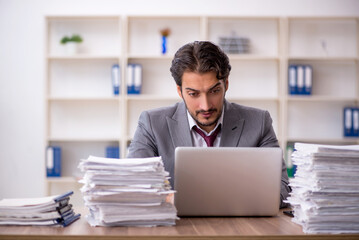 Obraz premium Young male employee and too much work in the office