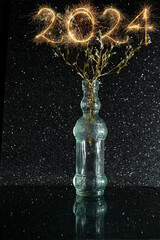 2024 number written with sparklers on a plant growing in a glass bottle