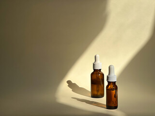 Two cosmetic transparent jars with serum on a nude background with sunlight on it. Beauty routine