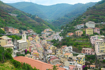 Cinque Terre, Italy - view of colorful houses, hills, vineyards of Riomaggiore, a seaside town on the Italian Riviera. Summer travel vacation background. Postcard from Europe. Italian architecture.